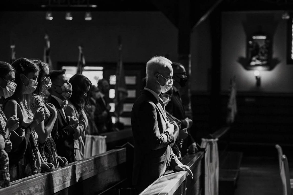 Osoby w maseczkach modlą się w kościele.