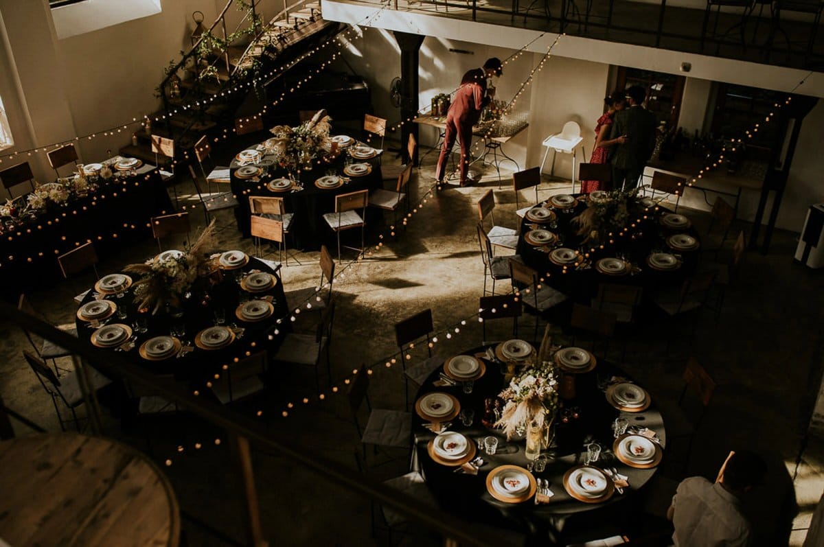 Elegancka sala weselna z okrągłymi stołami i dekoracjami.