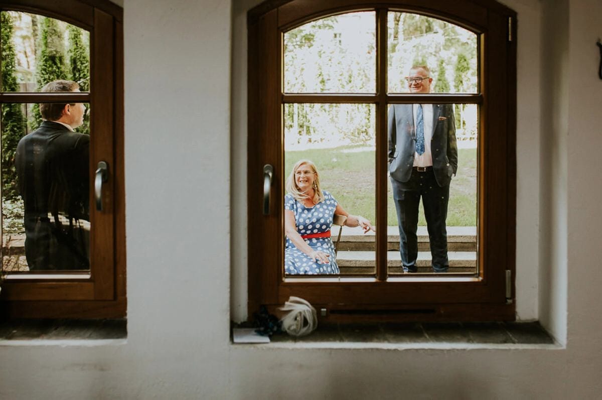 Trzy osoby rozmawiają przez okno.
