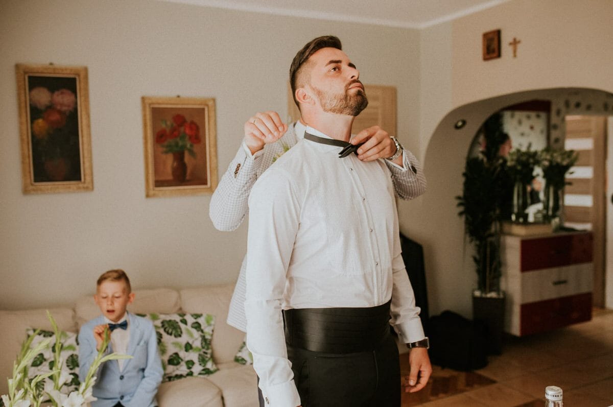 Zakładanie muszki przed weselem w salonie.