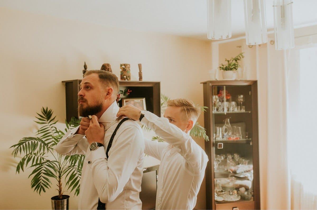 Dwoje mężczyzn ubierają się elegancko w pokoju.