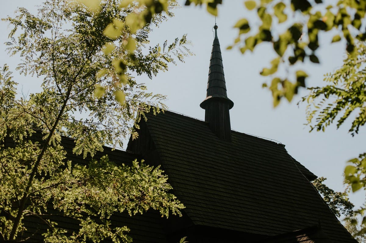 Drewniany kościół wśród zielonych drzew.