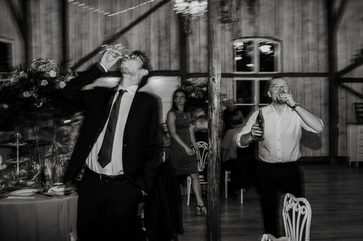 Mężczyźni piją alkohol na weselu w stodole