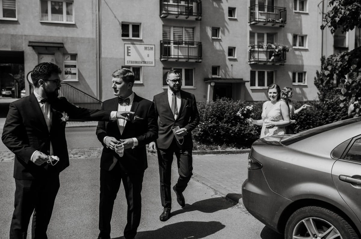 Grupa elegancko ubranych ludzi przed budynkiem.
