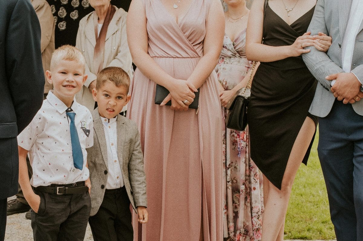 Dzieci i dorośli w eleganckich strojach na uroczystości.