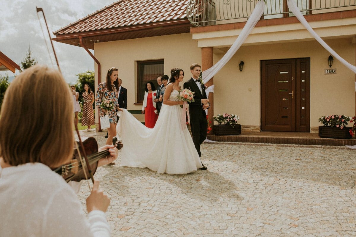 Para młoda przed domem, grająca skrzypaczka.