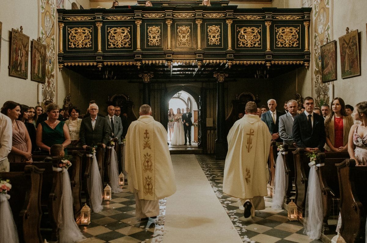 Ceremonia ślubna w kościele, księża i goście.