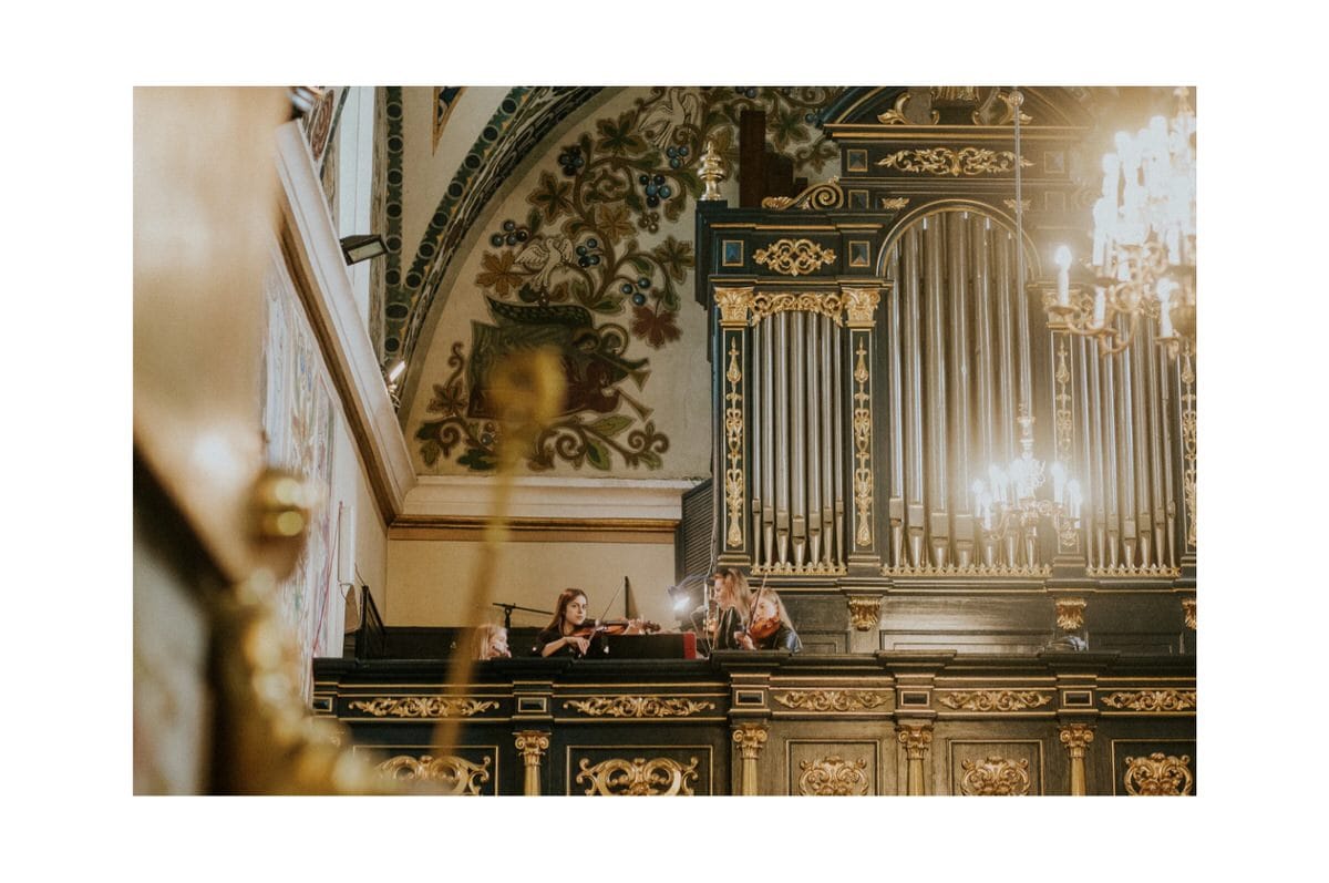 Muzycy grają na skrzypcach przed organami w kościele.