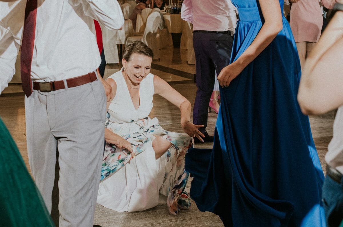 Kobieta w białej sukni uśmiecha się na przyjęciu.