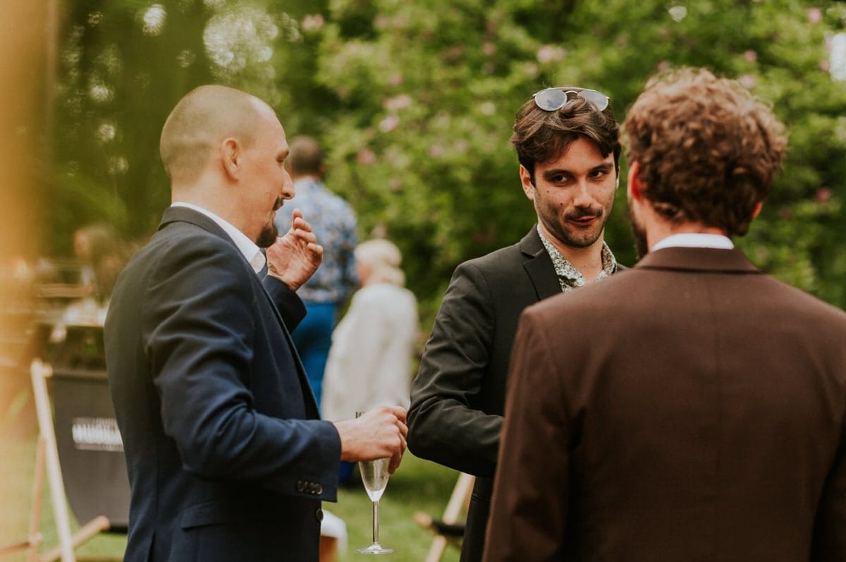 Ludzie rozmawiają na świeżym powietrzu, elegancko ubrani.