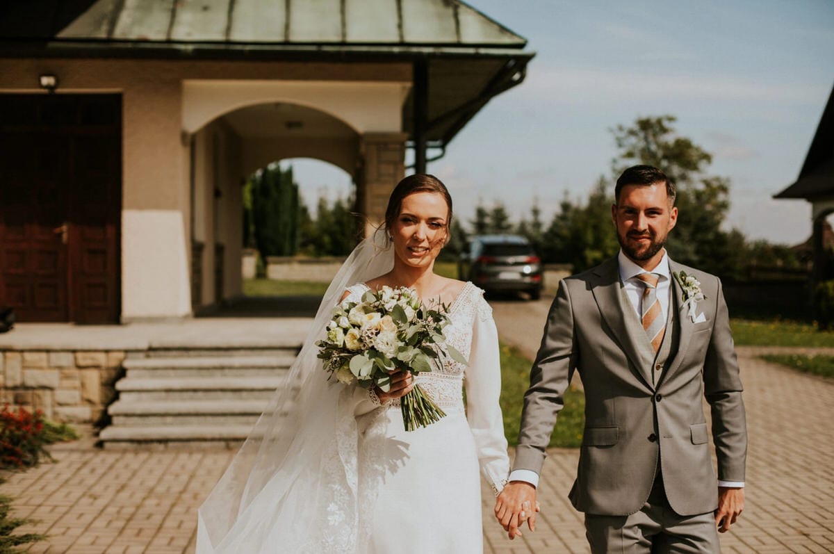 Para młoda idzie przed kościołem.