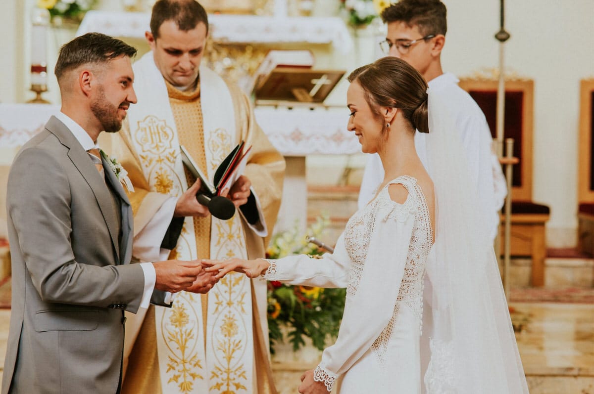 Para młoda wymienia obrączki w kościele.