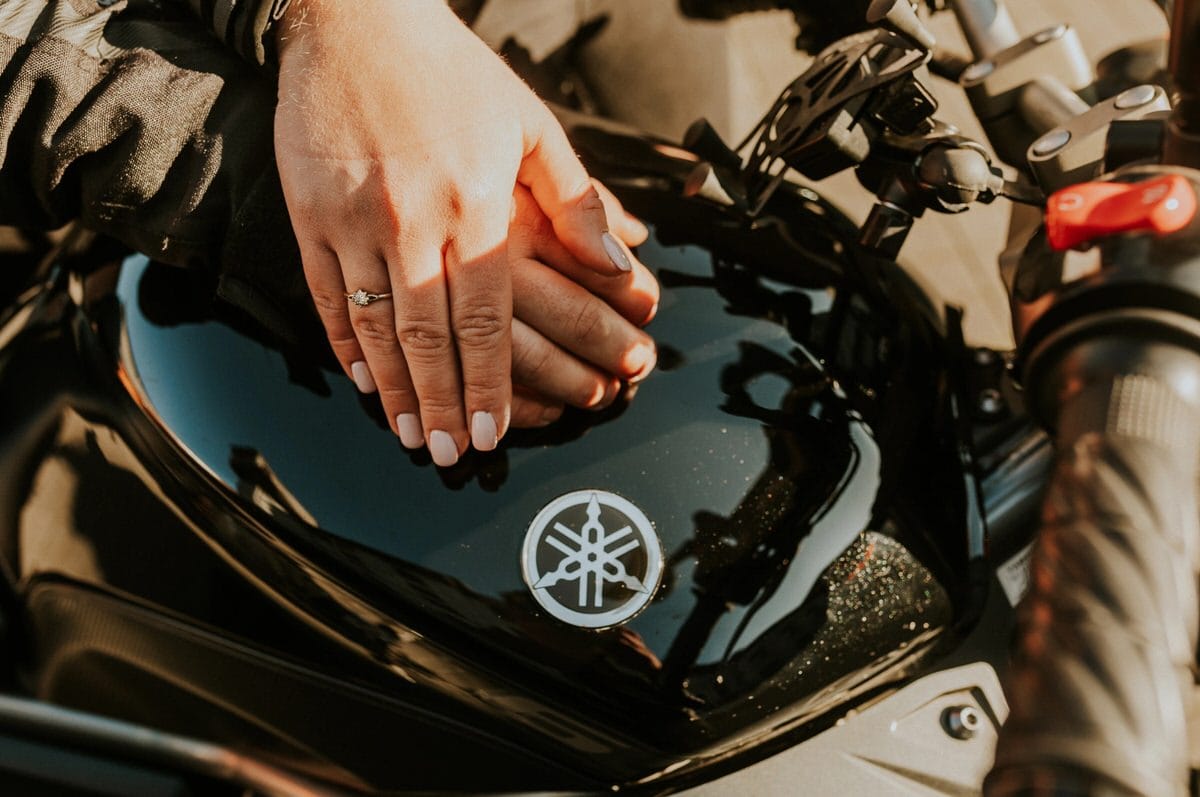 Ręce na motocyklu Yamaha z pierścionkiem zaręczynowym.