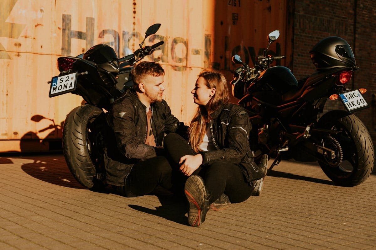 Para siedzi przy motocyklach na słońcu.