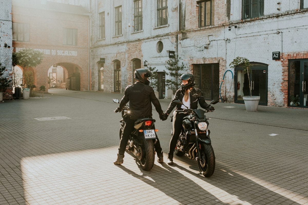 Para motocyklistów trzyma się za ręce w słońcu