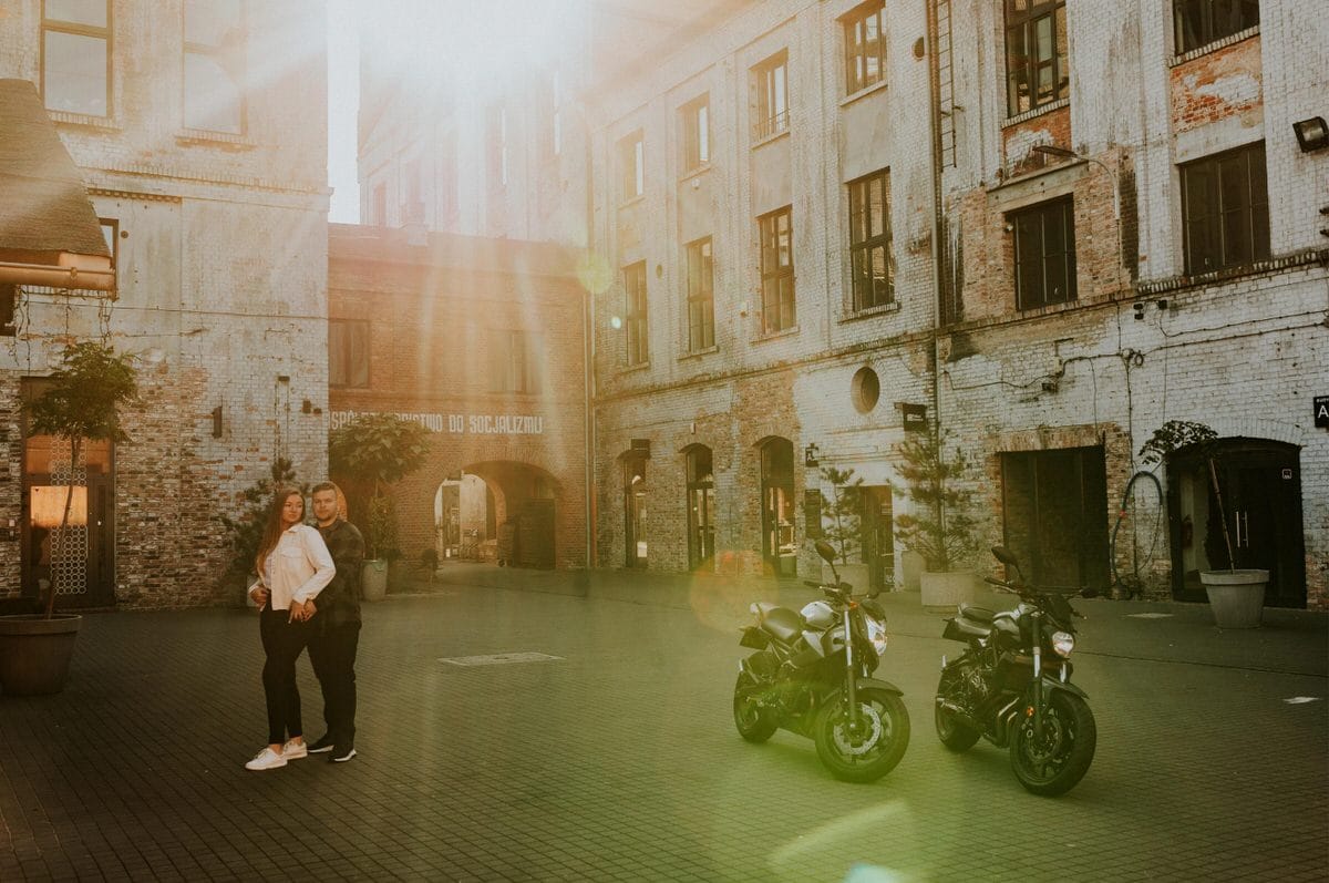 Para i motocykle na tle industrialnego budynku.