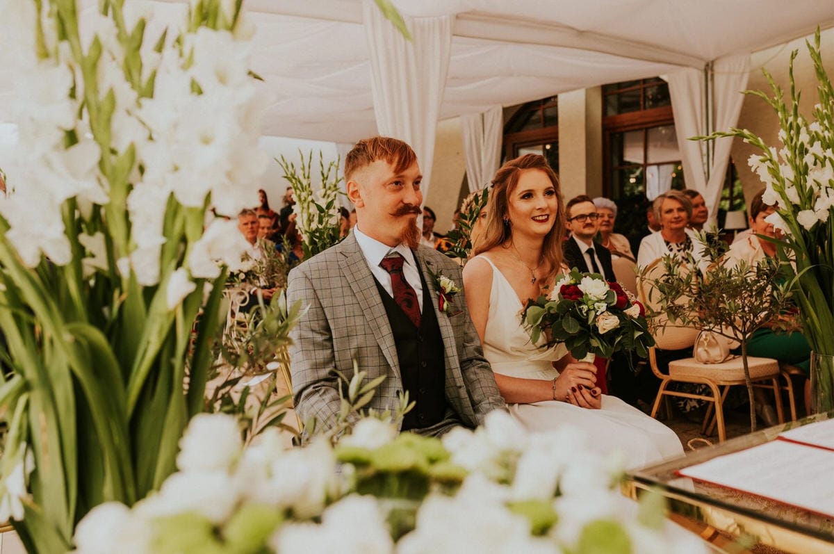 Para młoda na ceremonii ślubnej z bukietem kwiatów.