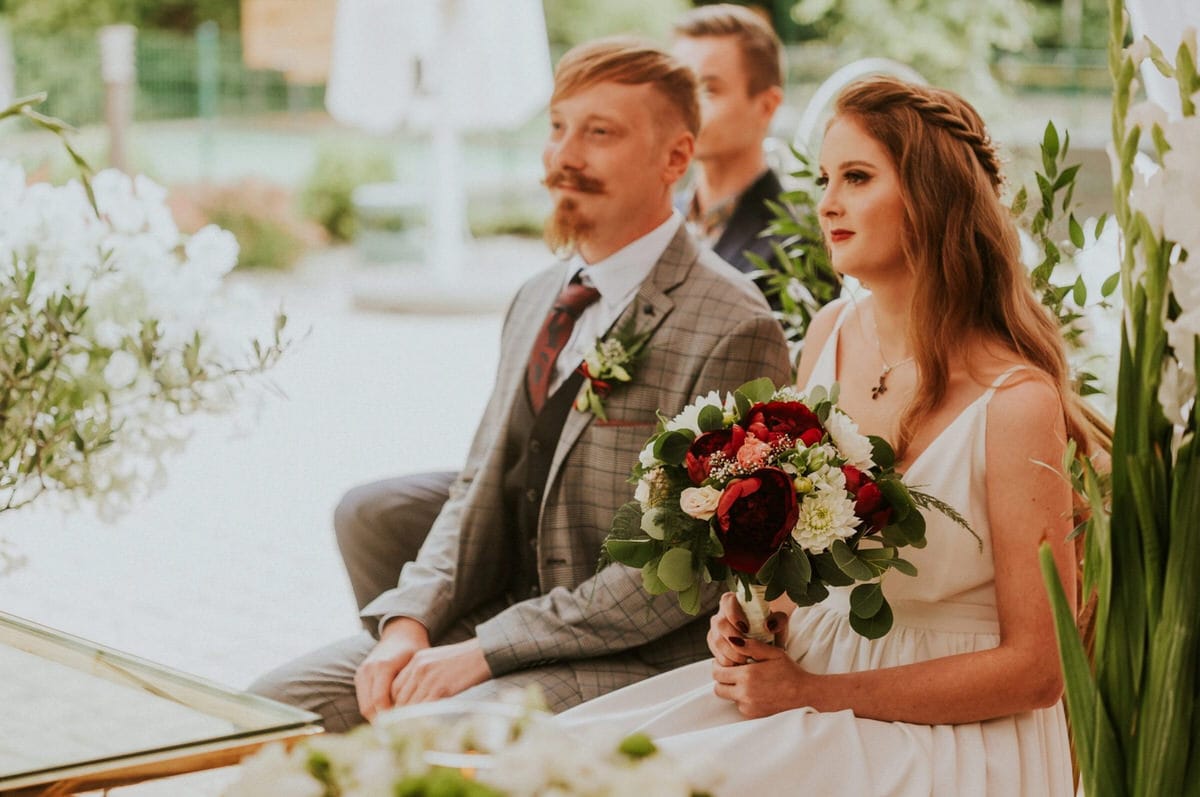 Para na ceremonii ślubnej z bukietem kwiatów.