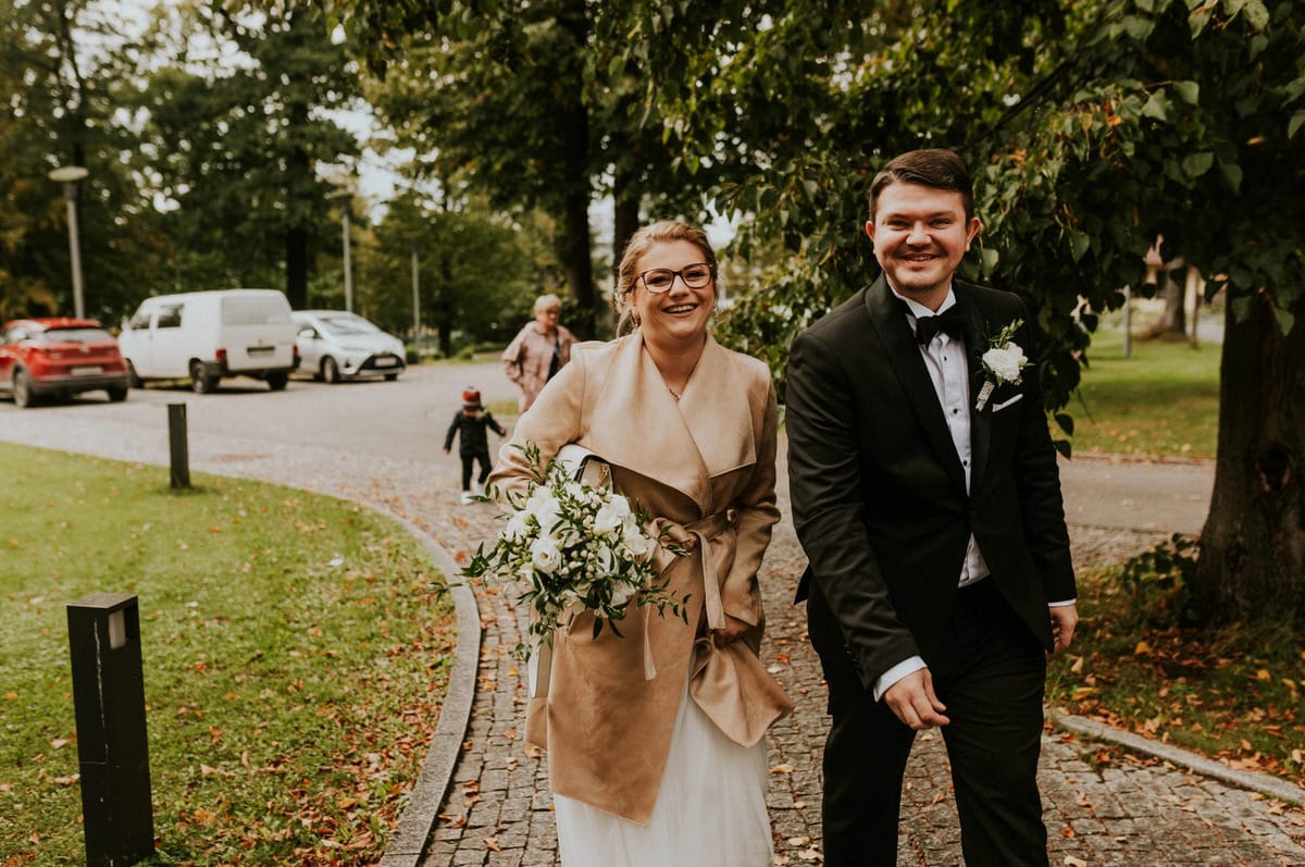 Para młoda spaceruje parkiem w dniu ślubu.