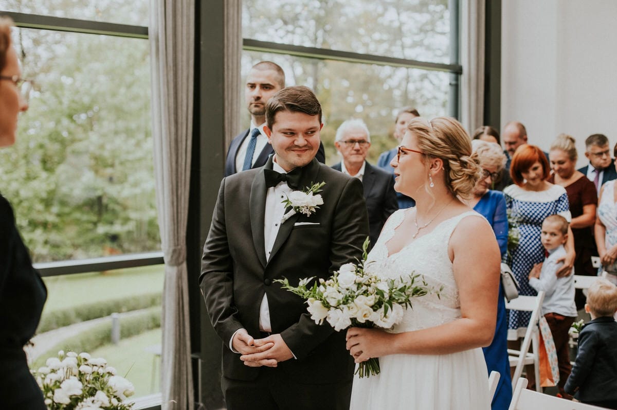 Para młoda podczas ceremonii ślubnej w otoczeniu gości.