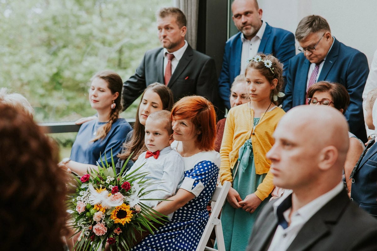 Grupa osób na uroczystości rodzinnej z kwiatami.