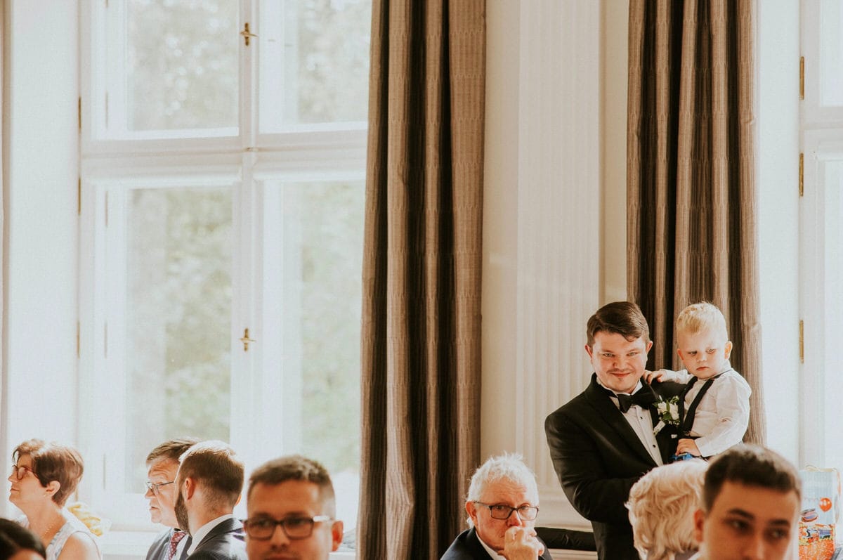 Przyjęcie weselne, goście przy stole, elegancki mężczyzna z dzieckiem.