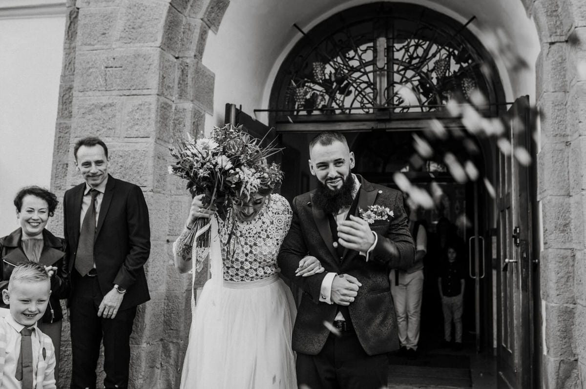 Para młoda wychodzi z kościoła zalana ryżem.