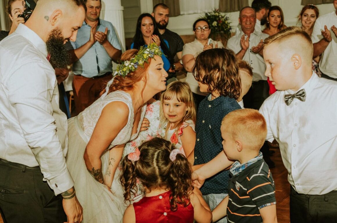 Para młoda bawiąca się z dziećmi na weselu.
