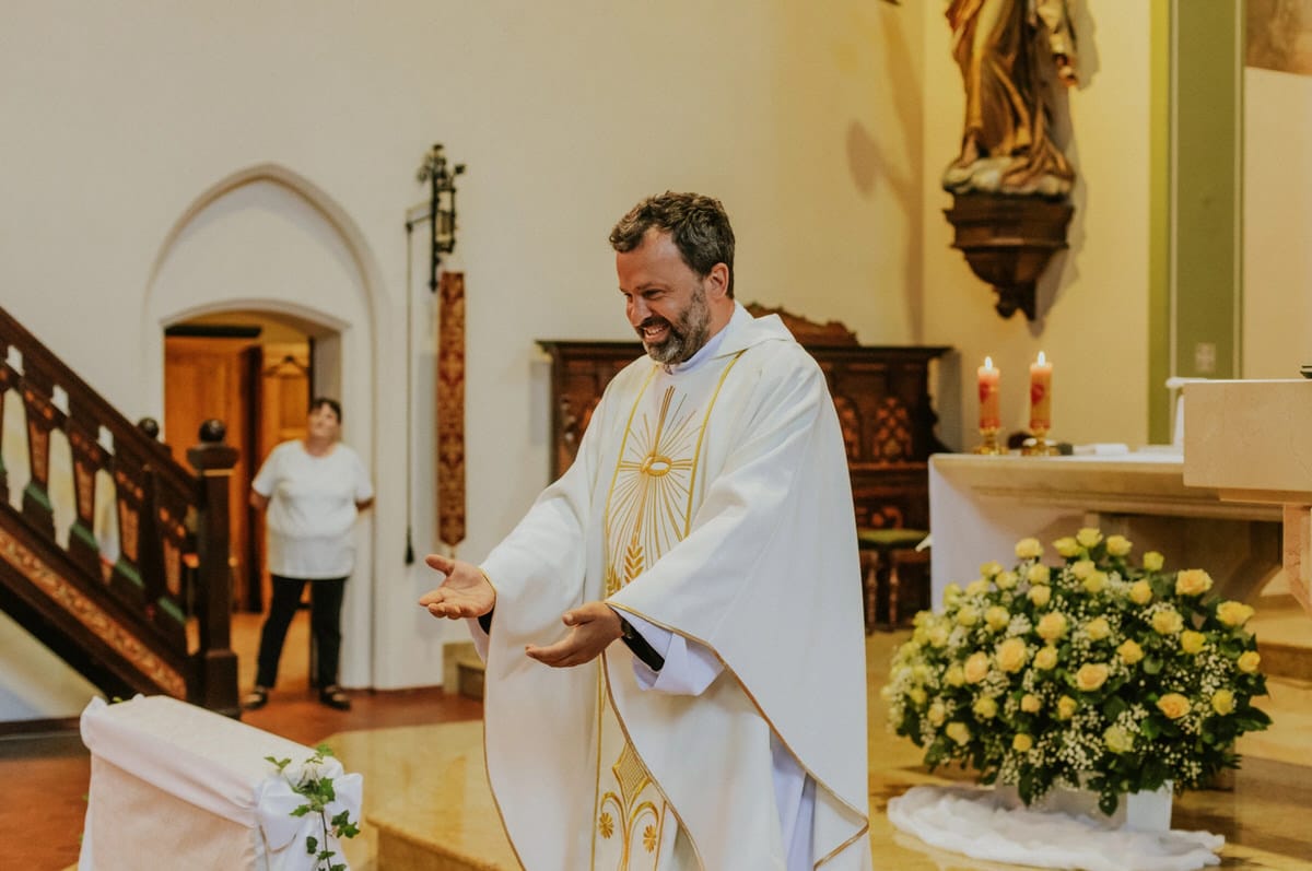 Ksiądz uśmiecha się podczas ceremonii w kościele.