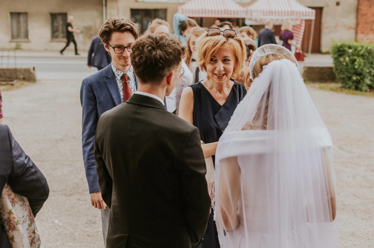 Goście rozmawiają przed ślubem, kobieta w welonie.