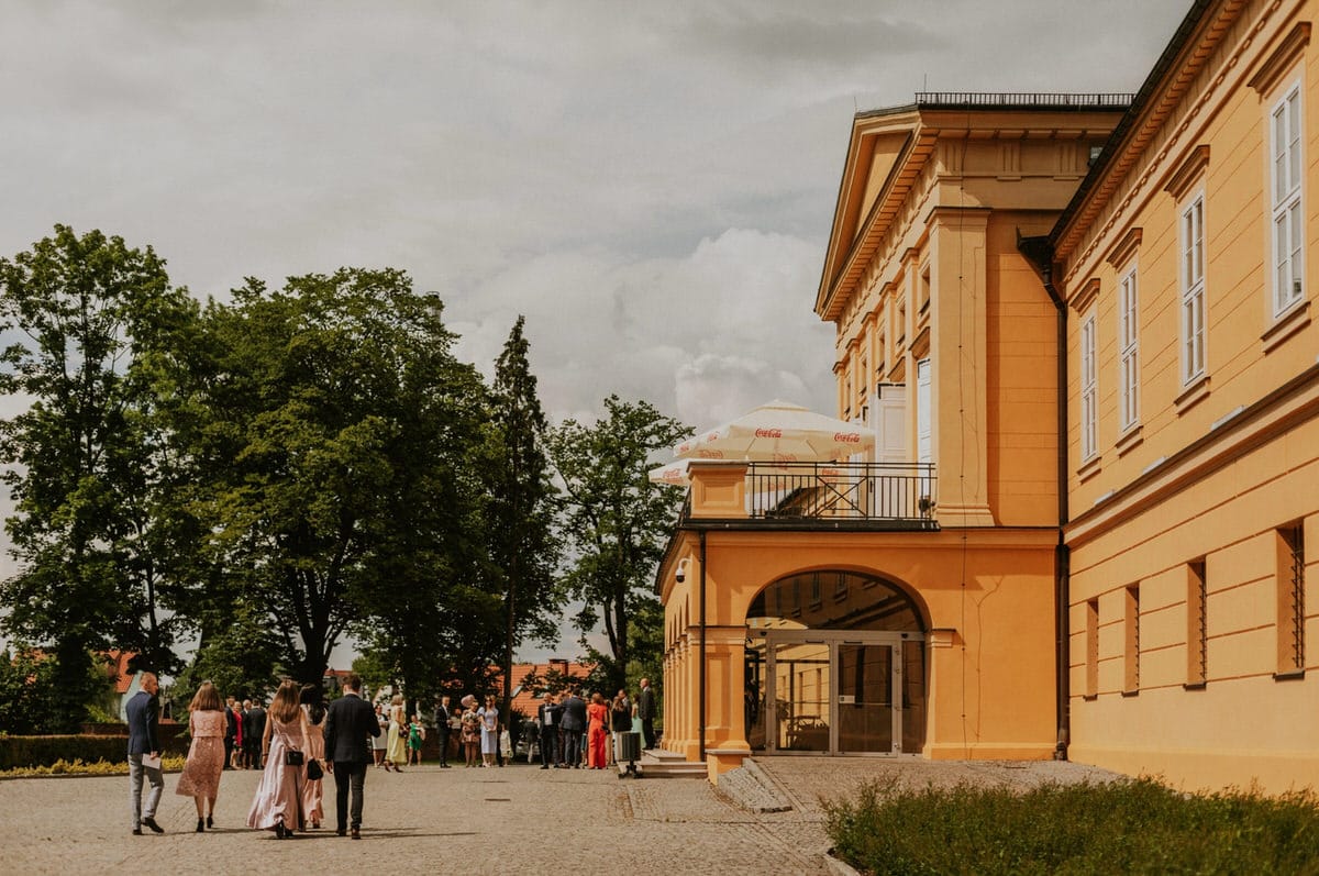 Ludzie przed zabytkowym budynkiem w parku.