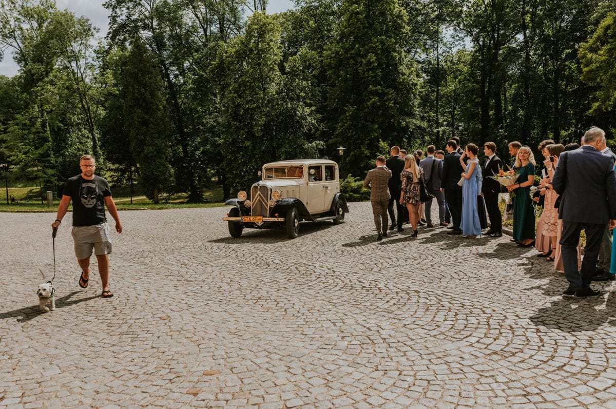 Stary samochód i goście weselni na zewnątrz
