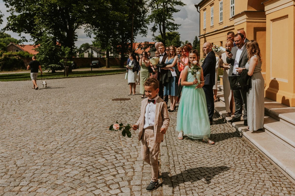 Dzieci z kwiatami podczas uroczystości na zewnątrz.