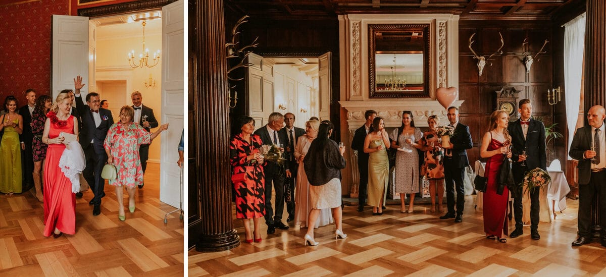 Grupa ludzi świętujących na eleganckim przyjęciu w pałacowym wnętrzu.