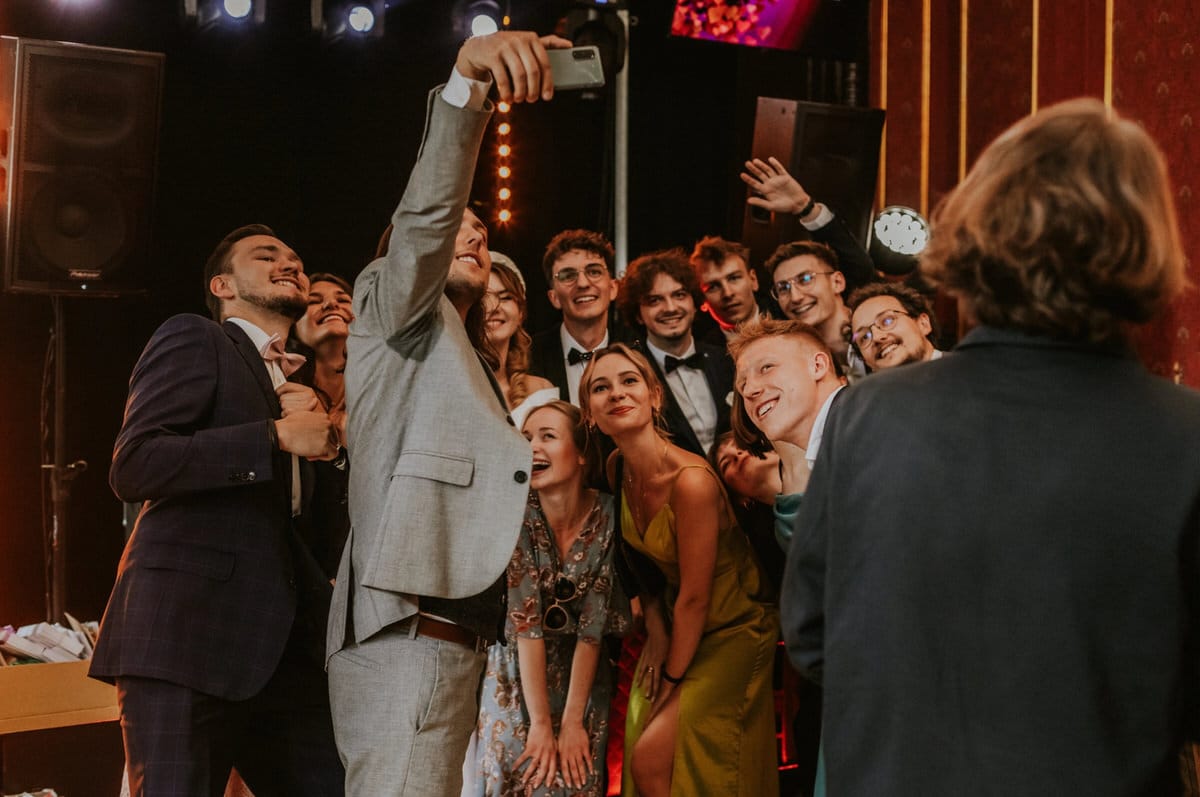 Grupa osób robiąca selfie na imprezie.