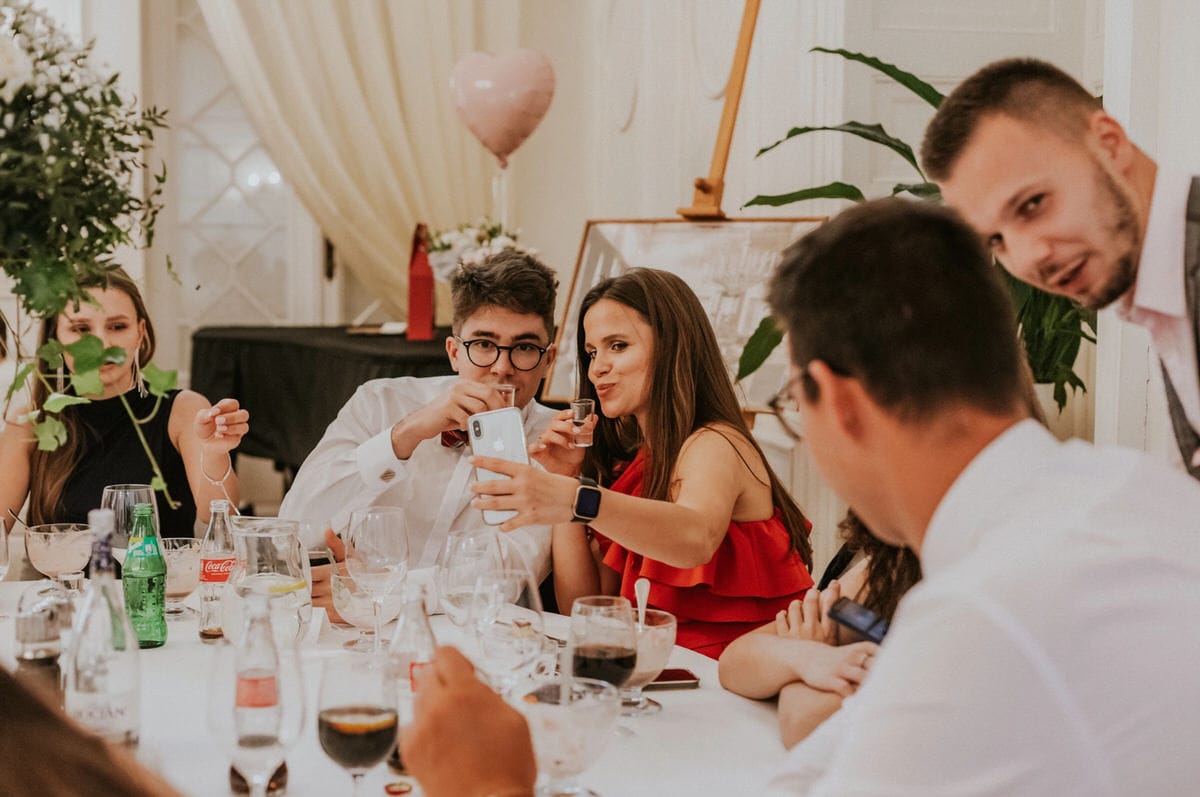 Ludzie robią selfie przy stole na imprezie.