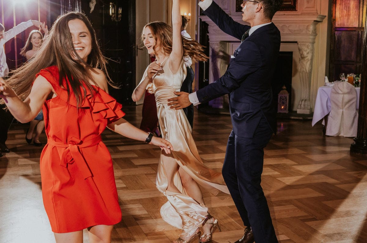 Ludzie tańczą na przyjęciu w eleganckim wnętrzu.