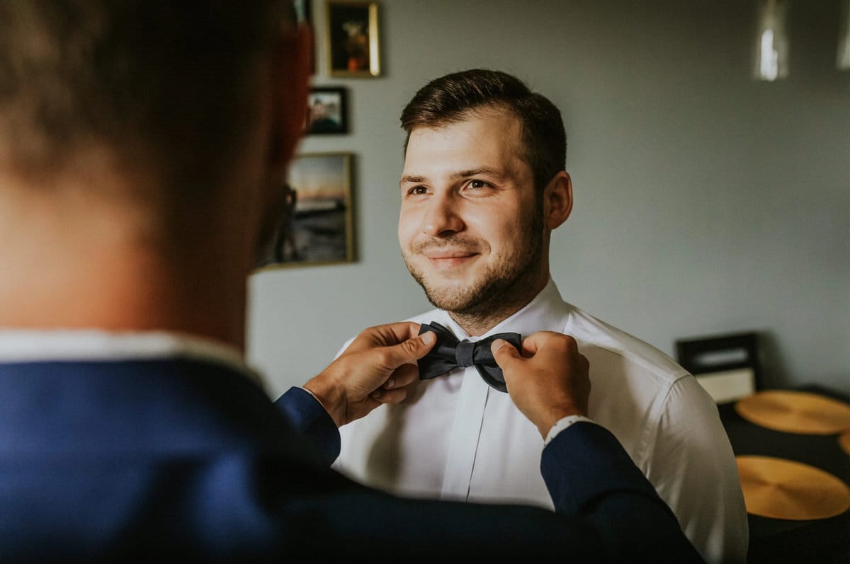 Mężczyzna przygotowuje się, wiąże muchę, uśmiechnięty