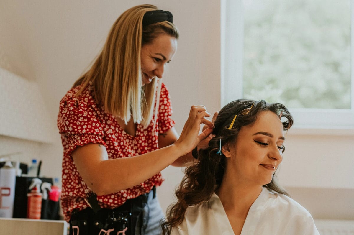 Stylizacja fryzury uśmiechniętej kobiety w salonie.