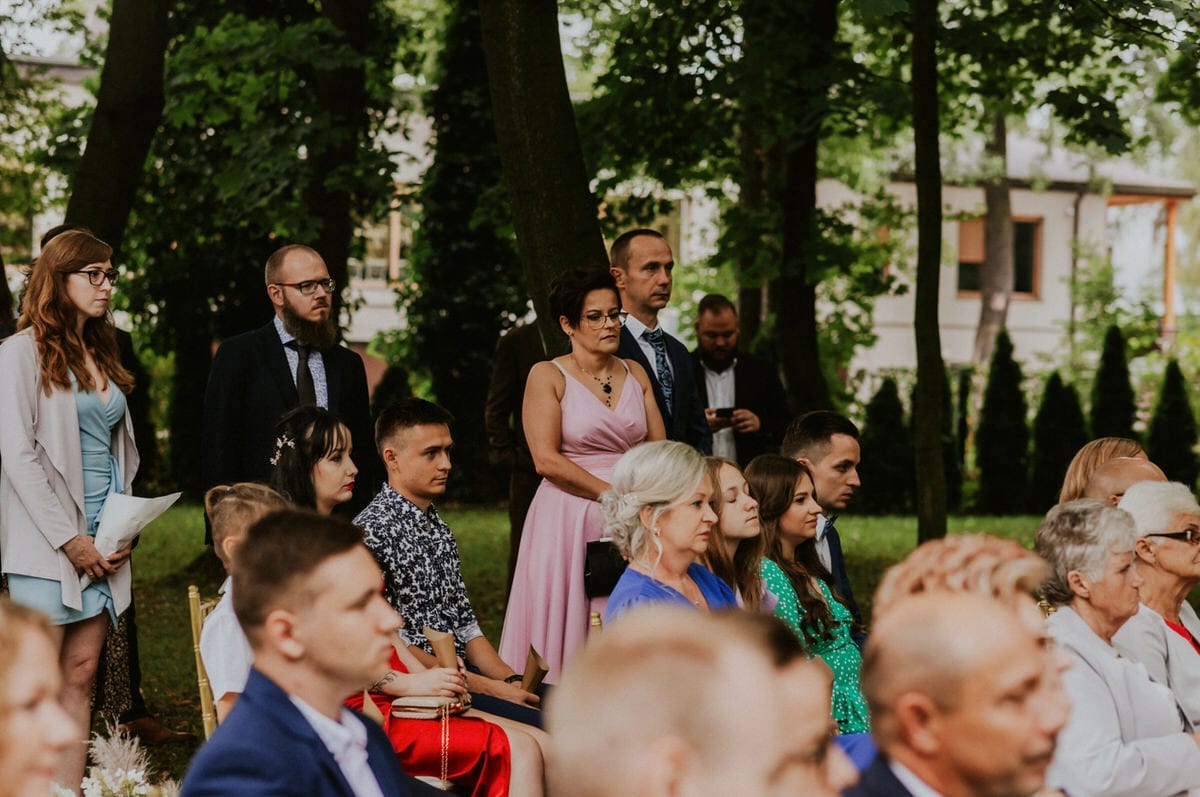 Goście na plenerowej ceremonii ślubnej w ogrodzie.