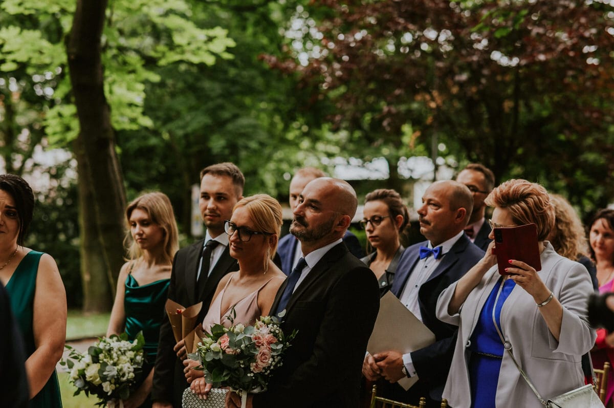 Goście weselni na ceremonii w ogrodzie.
