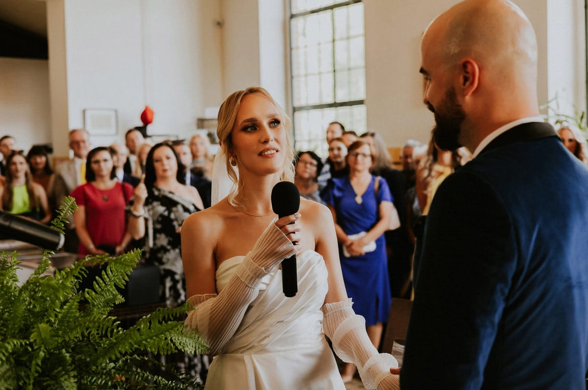 Ślubna ceremonia, pani mówi do mikrofonu.