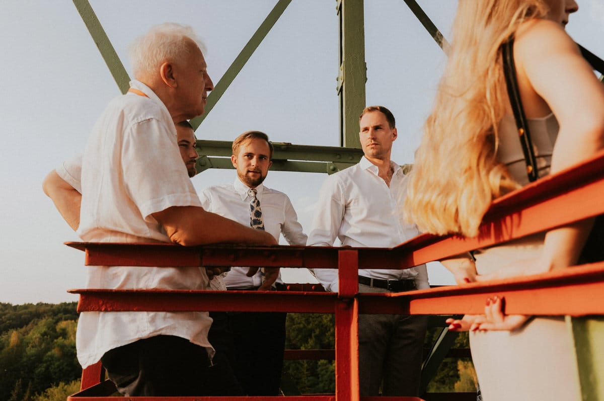Grupa ludzi na wieży widokowej o zachodzie słońca.