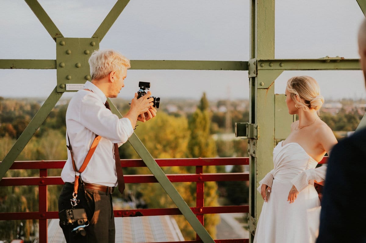 Fotograf robi zdjęcie pannie młodej na moście.