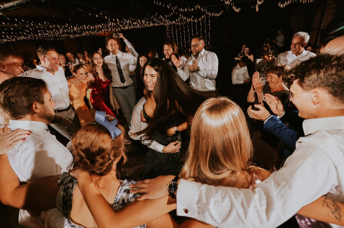 Grupa ludzi tańczy na weselu.